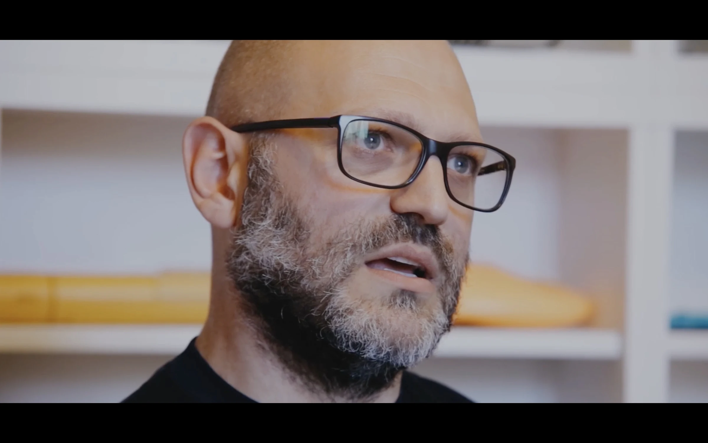 An Italian designer in glasses speaking during an interview in his studio