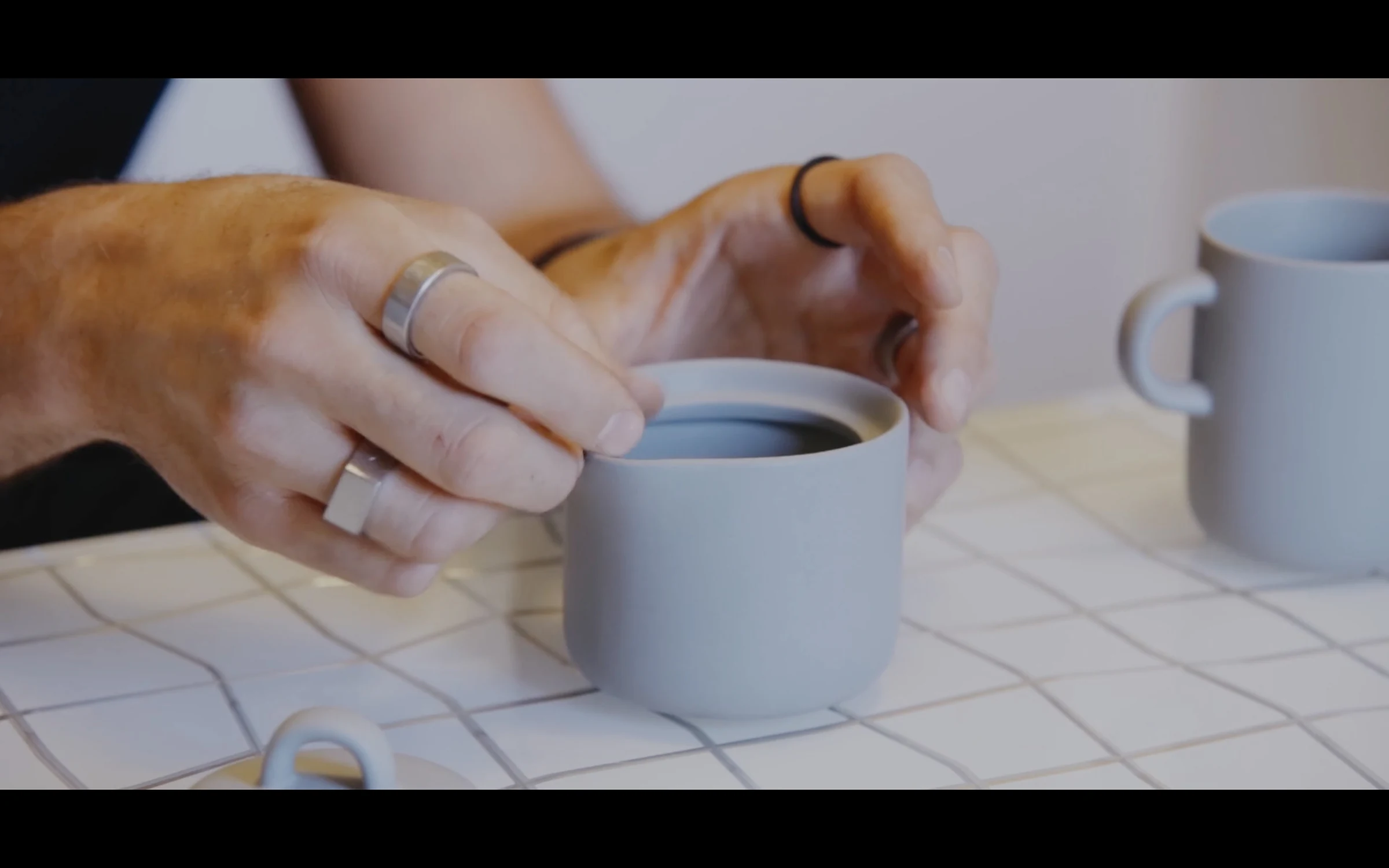 Hands cupped around an espresso cup on a marble table