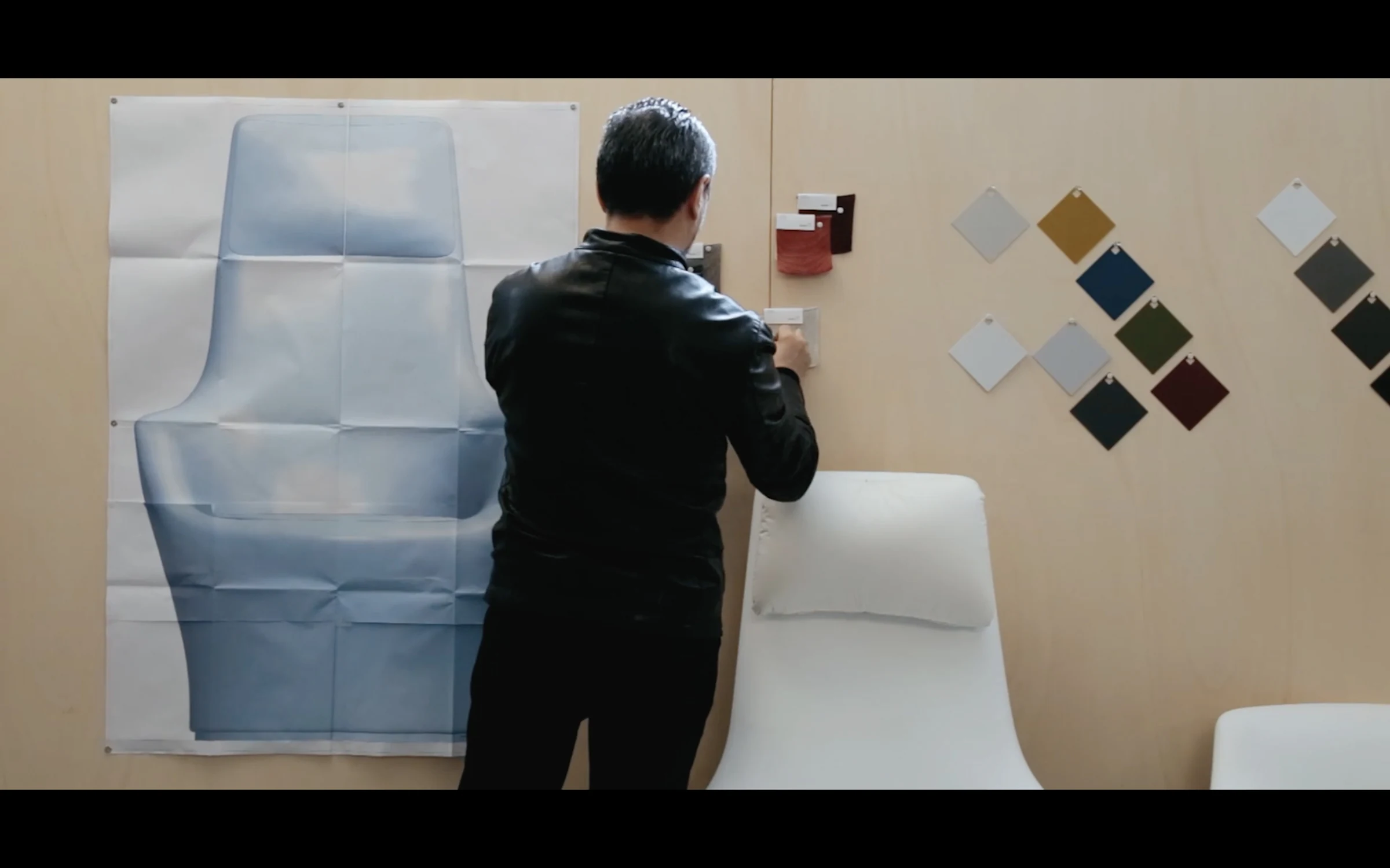 A designer studying material swatches pinned to a studio wall